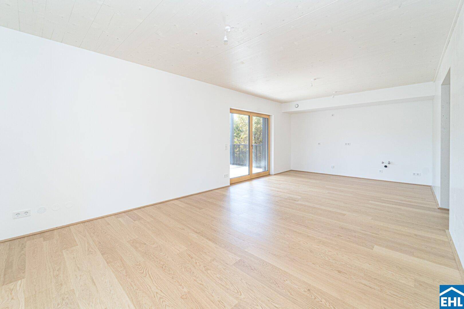 Weitläufiges Wohnzimmer mit Holzboden und Schiebetür zum Außenbereich, bietet viel Gestaltungspotenzial.