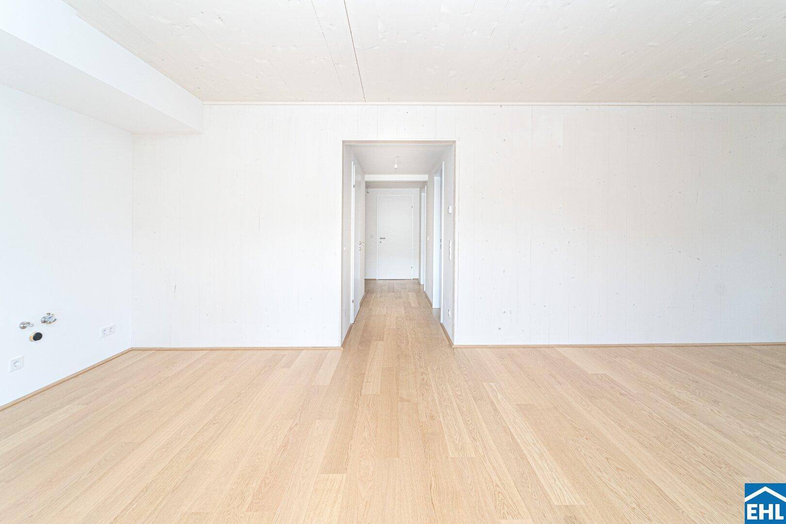 Langer, heller Flur mit Holzboden und weißen Wänden, der verschiedene Wohnbereiche verbindet.