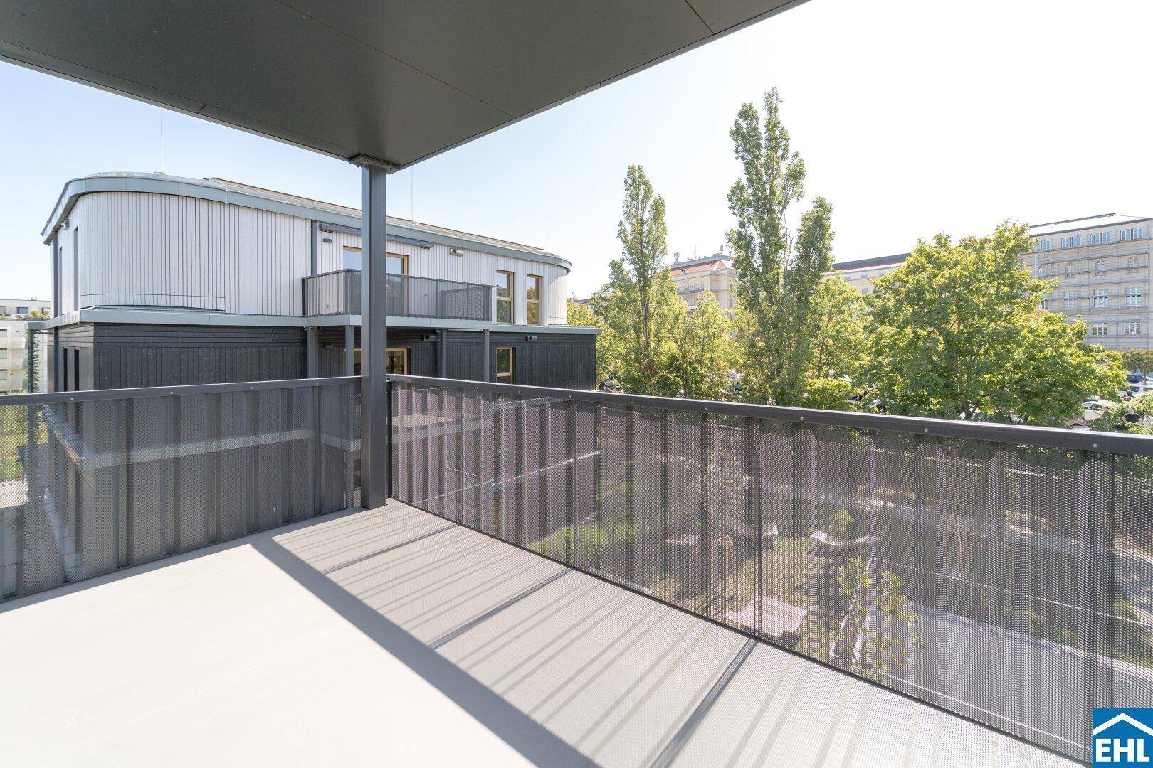 Heller Balkon mit modernem Metallgeländer und weitem Blick auf die Umgebung und Bäume.