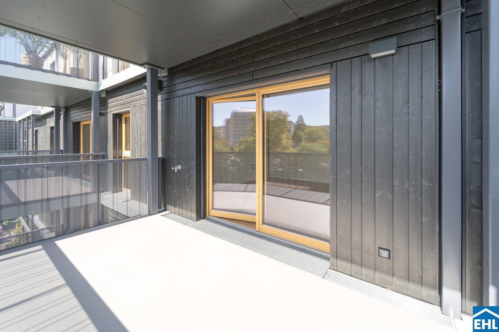 Moderner Balkon mit Holzwandverkleidung und Schiebetür, bietet einen privaten Außenbereich.