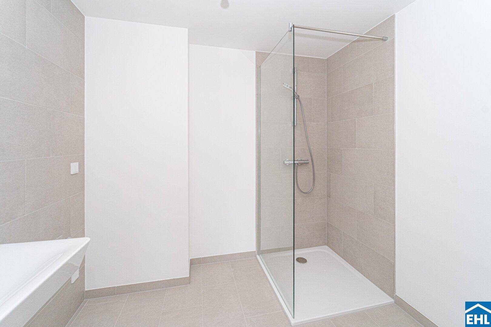 Modernes Badezimmer mit begehbarer Dusche und hellen Fliesen, minimalistisch und funktional.