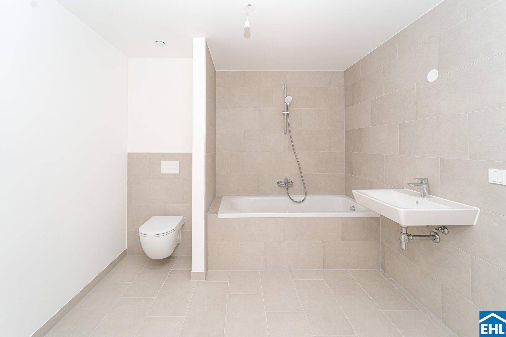 Modernes Badezimmer mit beigefarbenen Fliesen, Badewanne, Waschbecken und wandhängendem WC.
