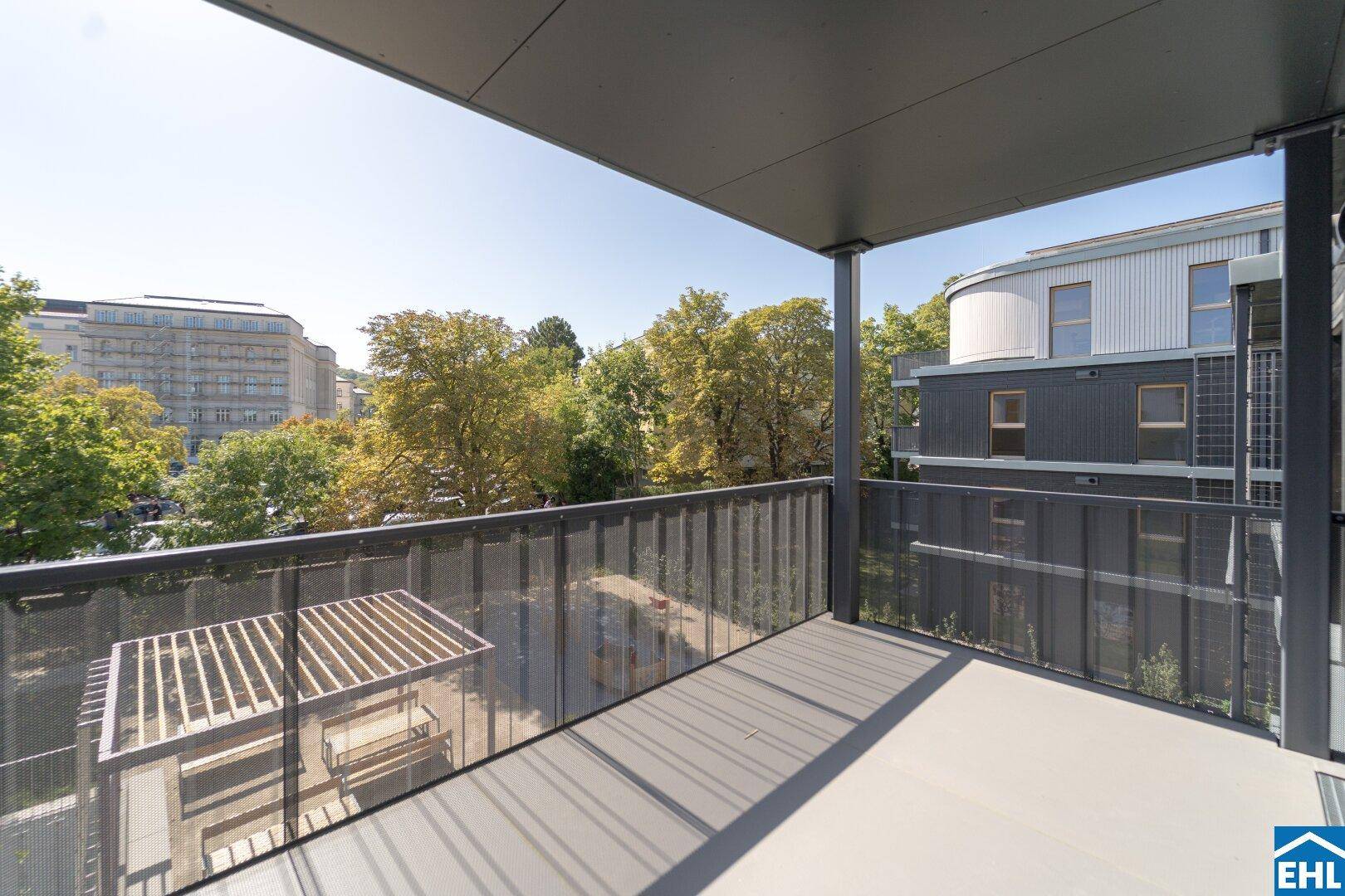 Geräumiger Balkon mit Metallgeländer und Blick auf die grüne Umgebung und andere Gebäude.