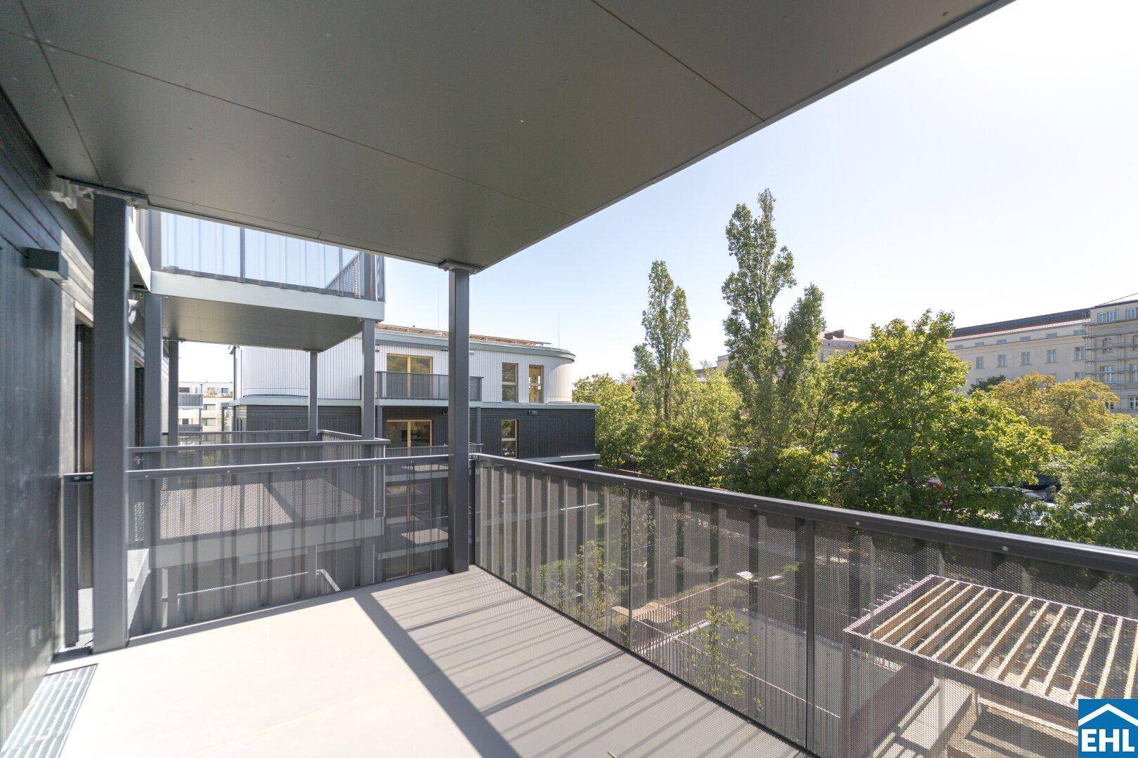 Heller Balkon mit modernem Metallgeländer und weitem Blick über die umliegenden Gebäude und Bäume.