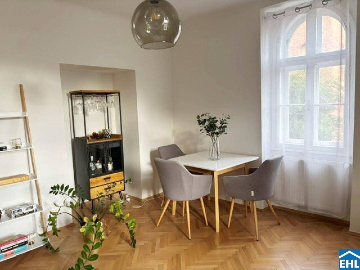 Heller Essbereich mit Holztisch, modernen Stühlen und einem dekorativen Regal mit Gläsern.