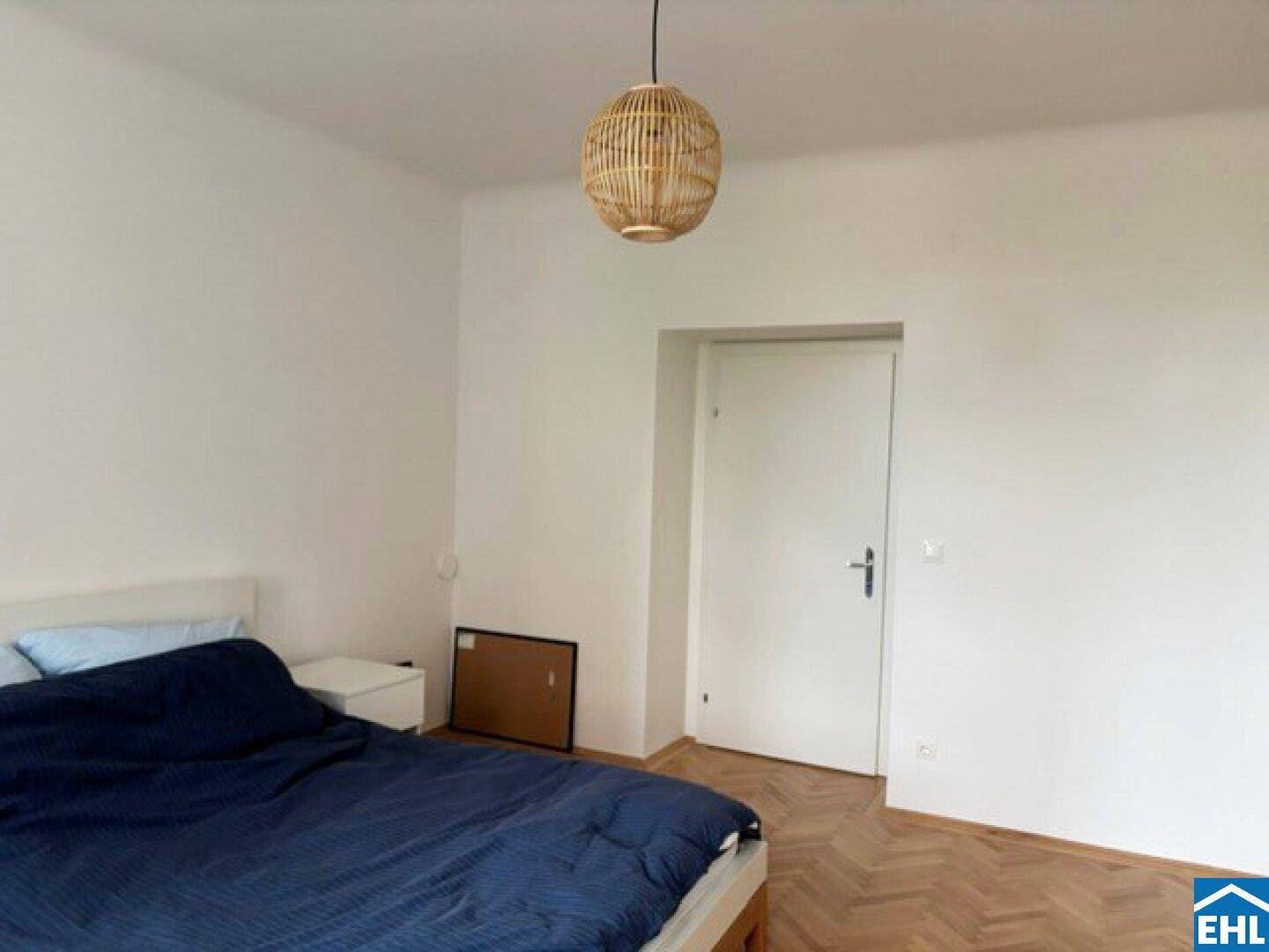 Schlafzimmer mit Holzboden und weißer Tür, bietet eine ruhige und helle Atmosphäre.