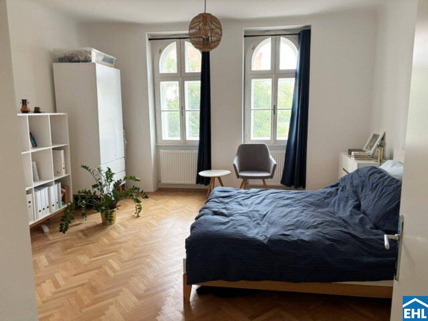 Geräumiges Schlafzimmer mit Parkettboden, zwei hohen Fenstern und moderner Einrichtung.