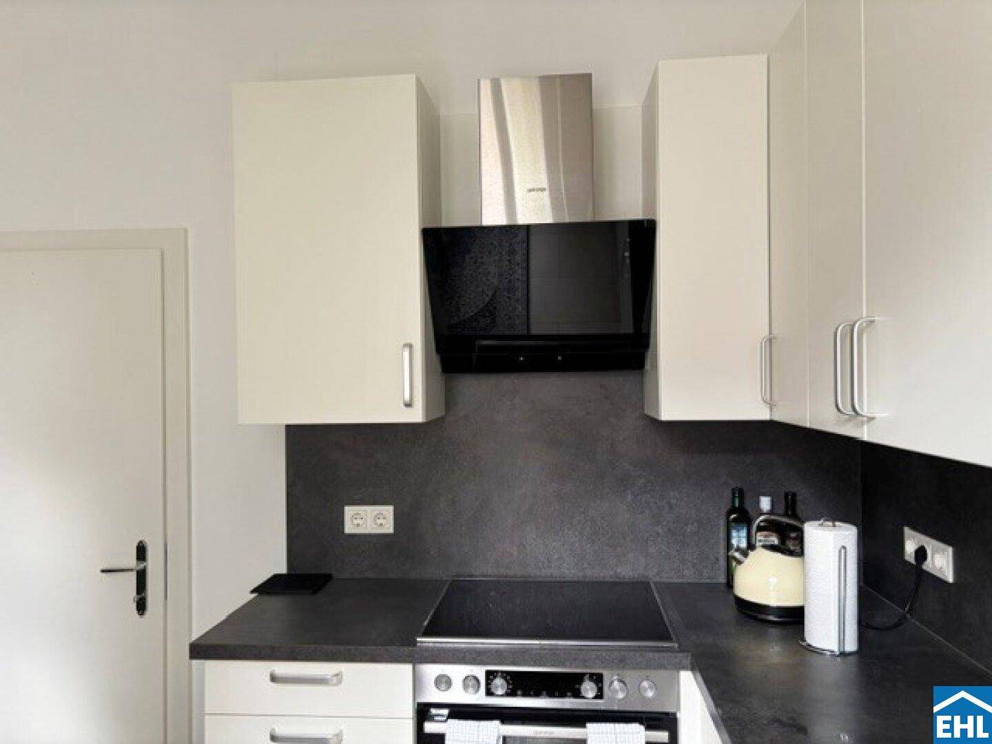 Küchenzeile mit Elektrokochfeld, Backofen und Dunstabzugshaube, in modernem Design.