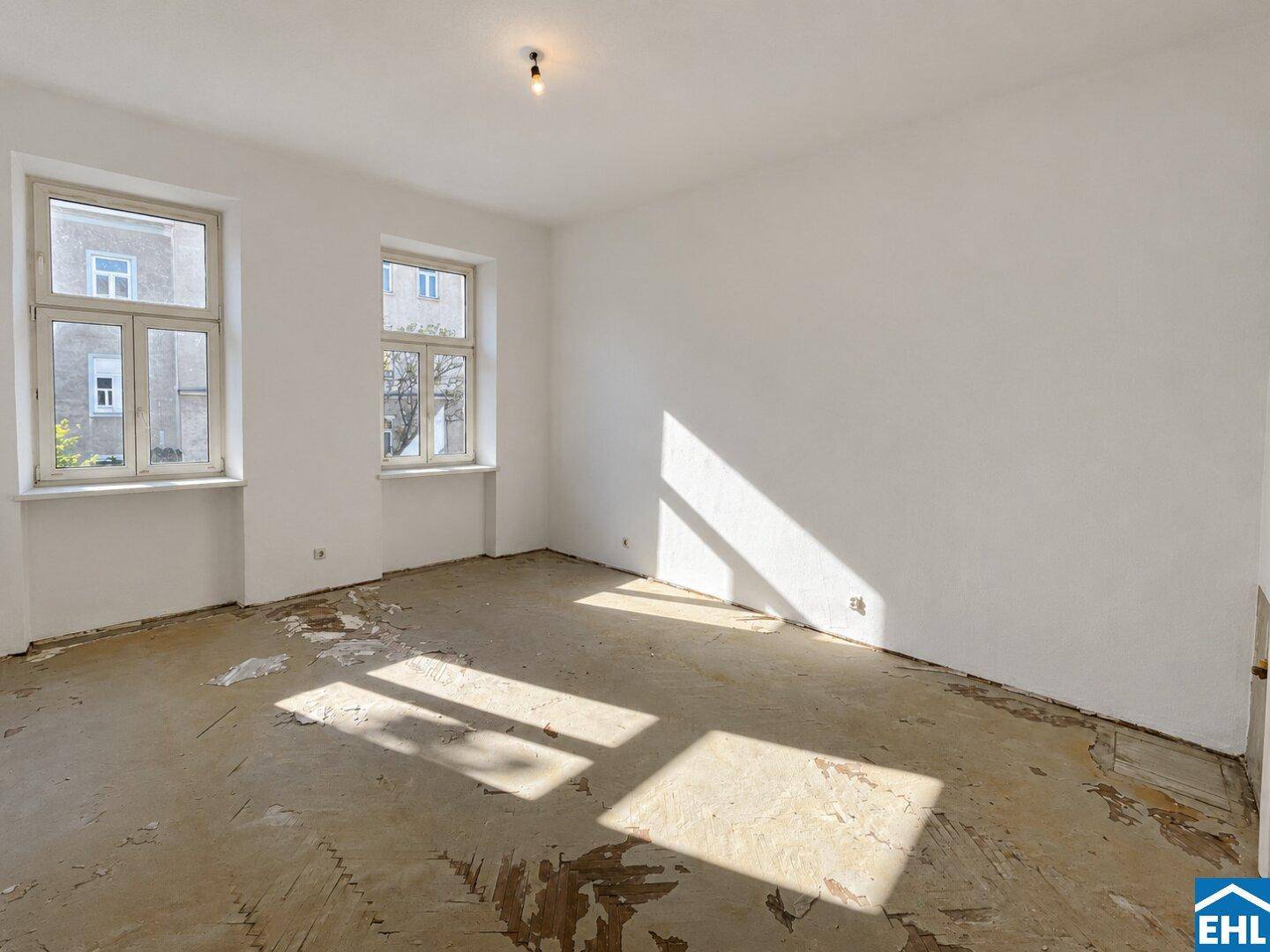 Geräumiger, heller Raum mit zwei Fenstern und viel Tageslicht, ideal für eine Renovierung.