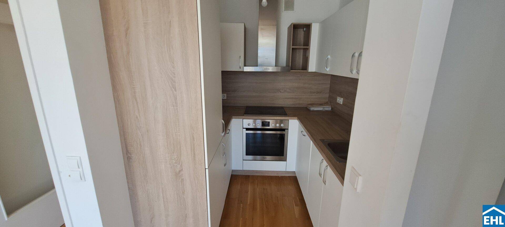 Moderne Einbauküche mit weißen Schränken, Holz-Arbeitsplatten und integrierten Geräten.
