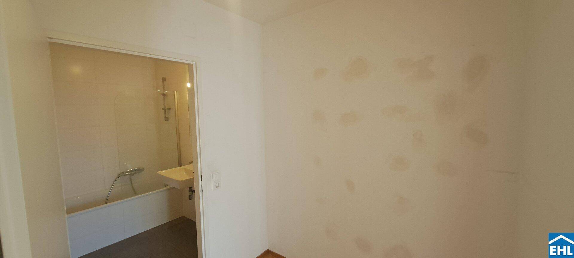 Badezimmer mit Badewanne und Waschbecken, sichtbar durch den Türrahmen.