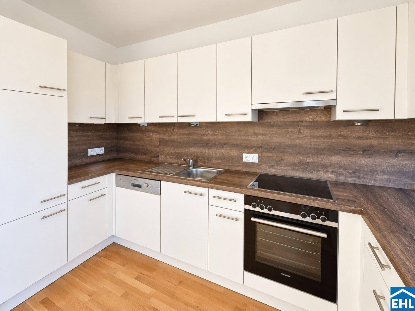 Moderne Einbauküche mit weißen Schränken, Holzoptik-Arbeitsplatten und integrierten Siemens-Geräten.