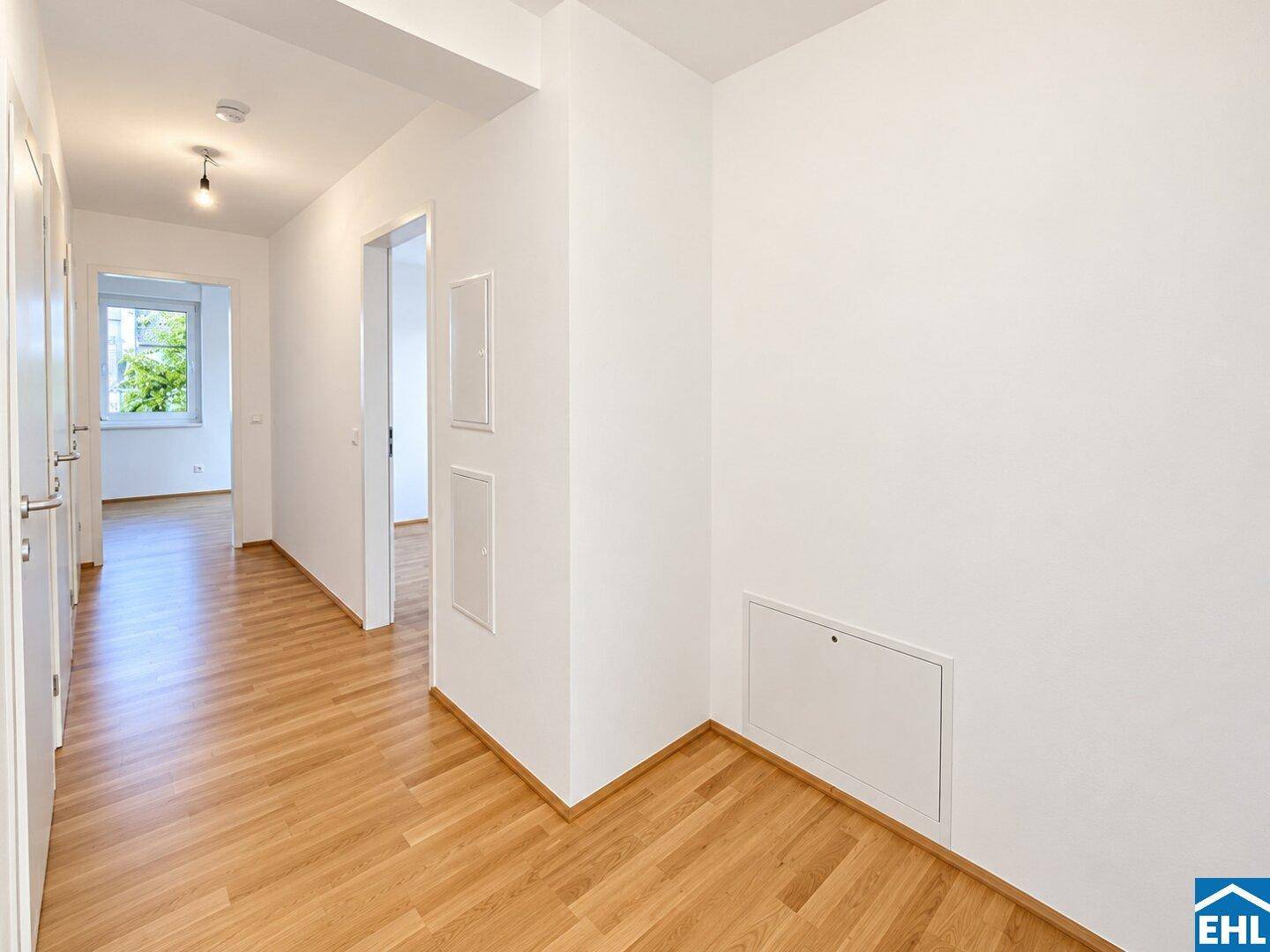 Heller Flur mit Holzboden, weißen Wänden und natürlichem Lichteinfall am Ende des Ganges.