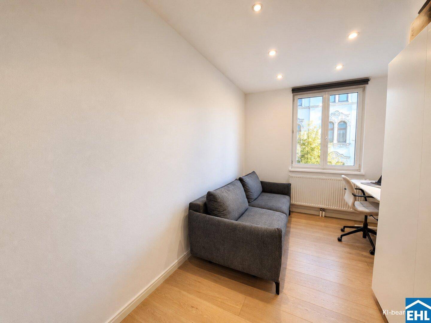 Ruhiges Arbeitszimmer mit Sofa, Schreibtisch und Fenster für natürliches Licht.