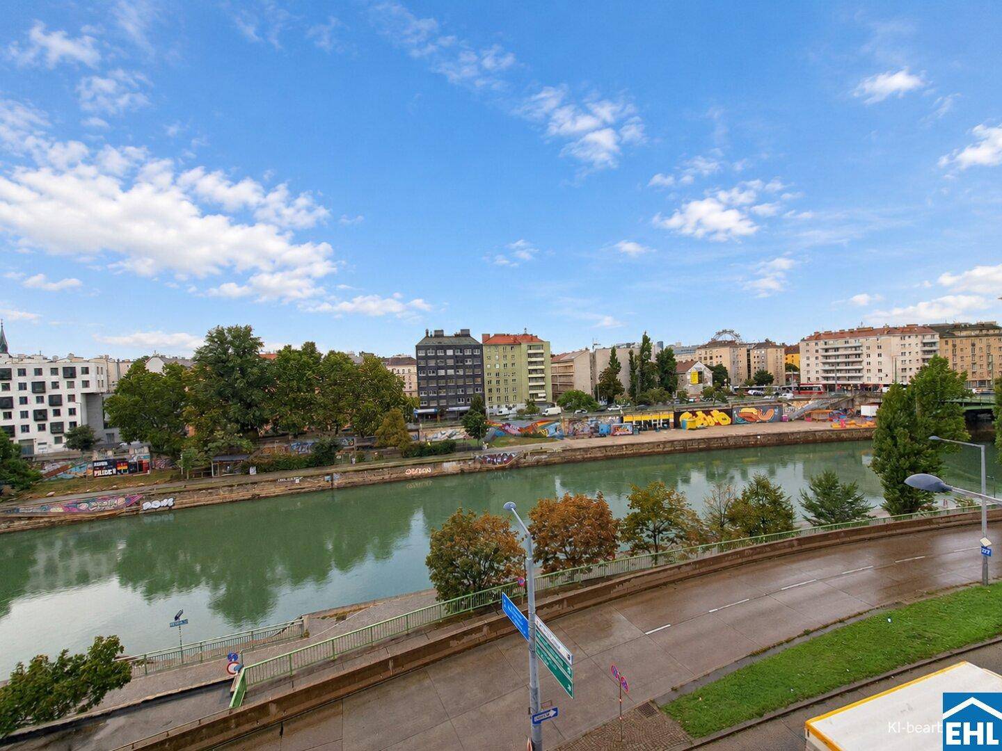 Weitläufiger Blick auf den Fluss und die städtische Umgebung mit Gebäuden und Bäumen.