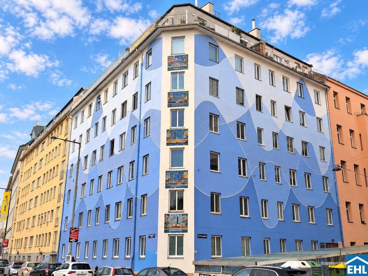 Auffällige Gebäudefassade mit blauen Wellenmustern und vielen Fenstern in der Stadt.