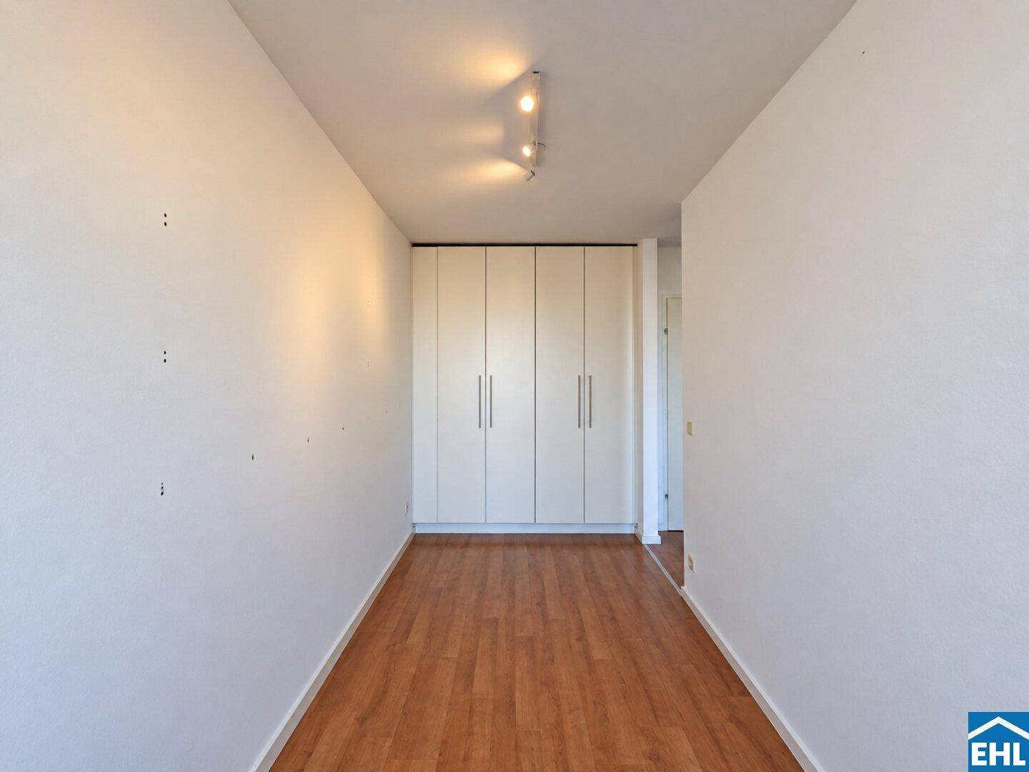 Langer, schmaler Raum mit praktischen Einbauschränken und Holzfußboden, bietet Stauraum.