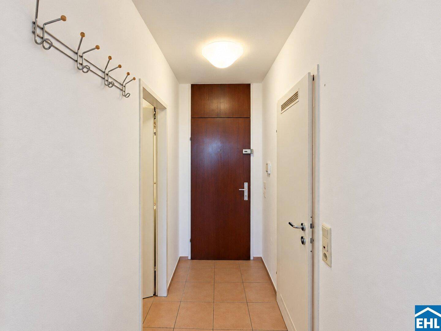 Heller Eingangsbereich mit Fliesenboden und Garderobe, einladend und funktional gestaltet.