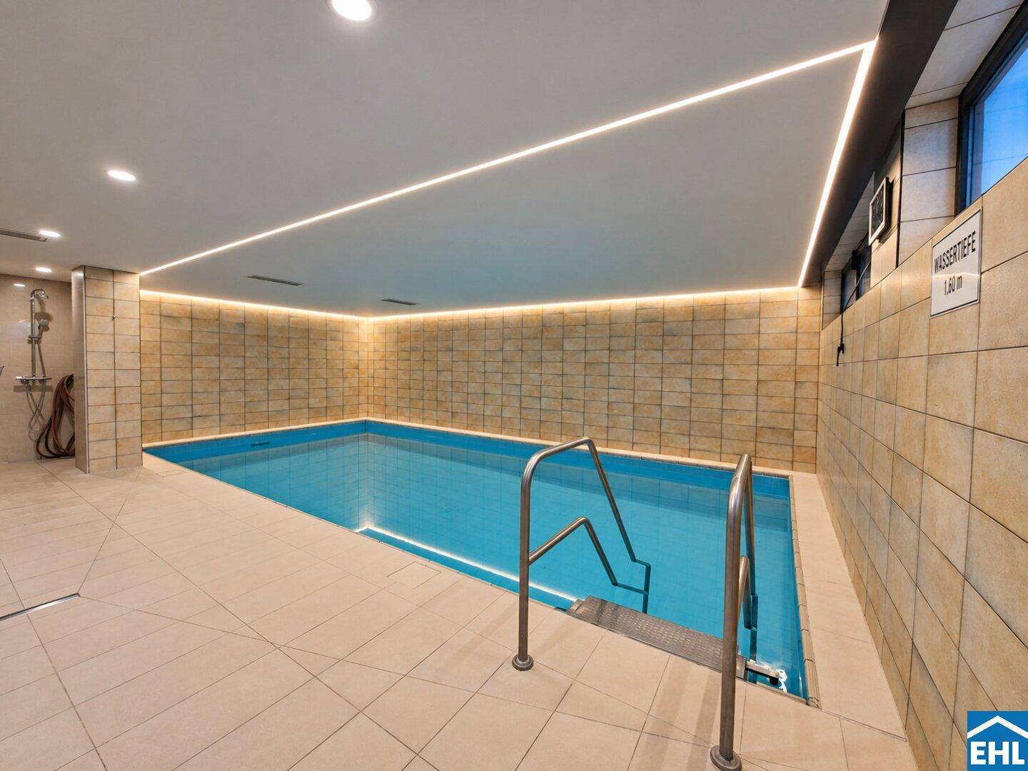 Modernes Hallenbad mit blauen Fliesen und stimmungsvoller LED-Beleuchtung, ideal zum Schwimmen.