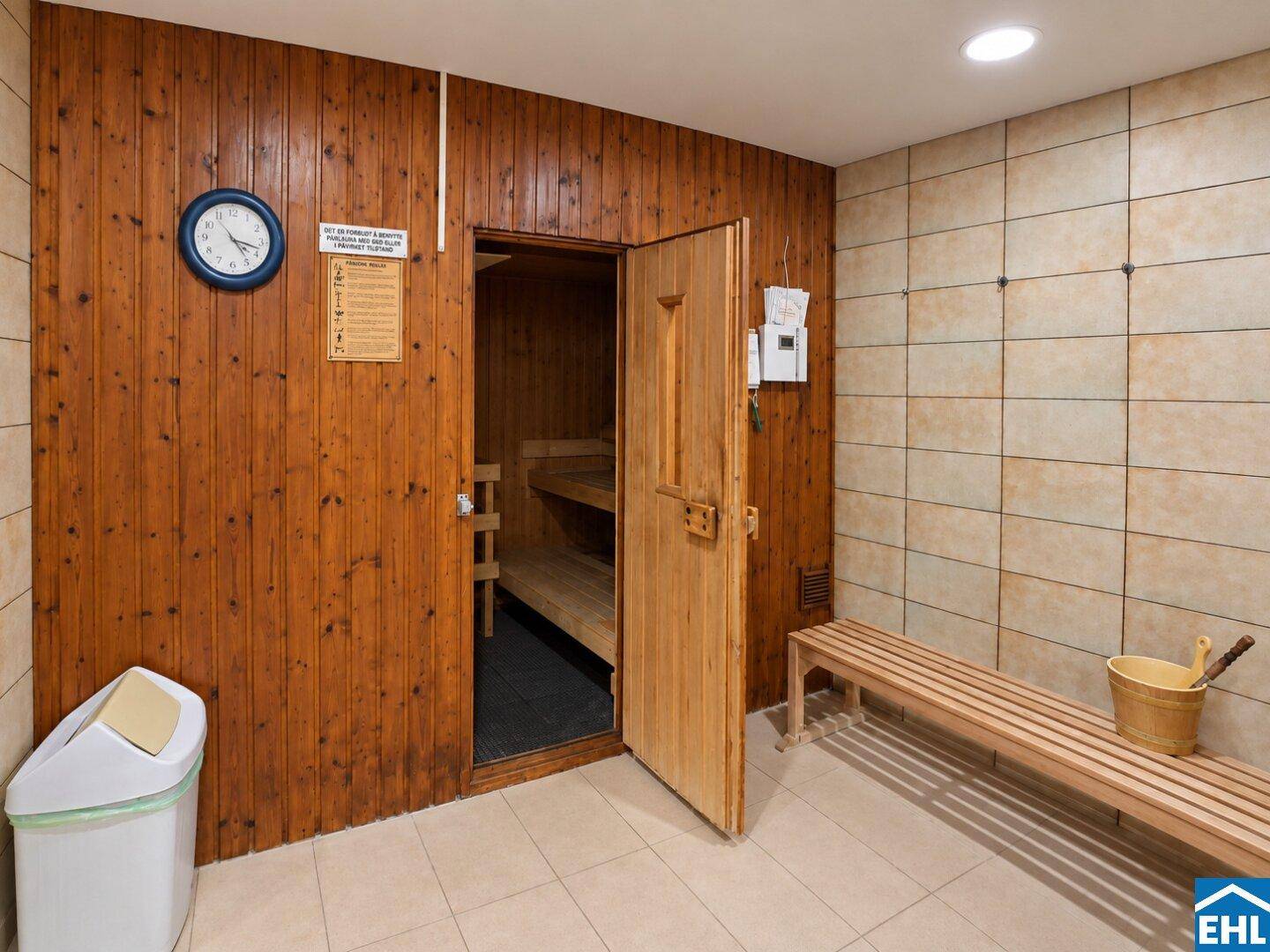 Traditionelle Holzsauna mit Sitzbänken und Zubehör, perfekt zur Entspannung nach dem Sport.