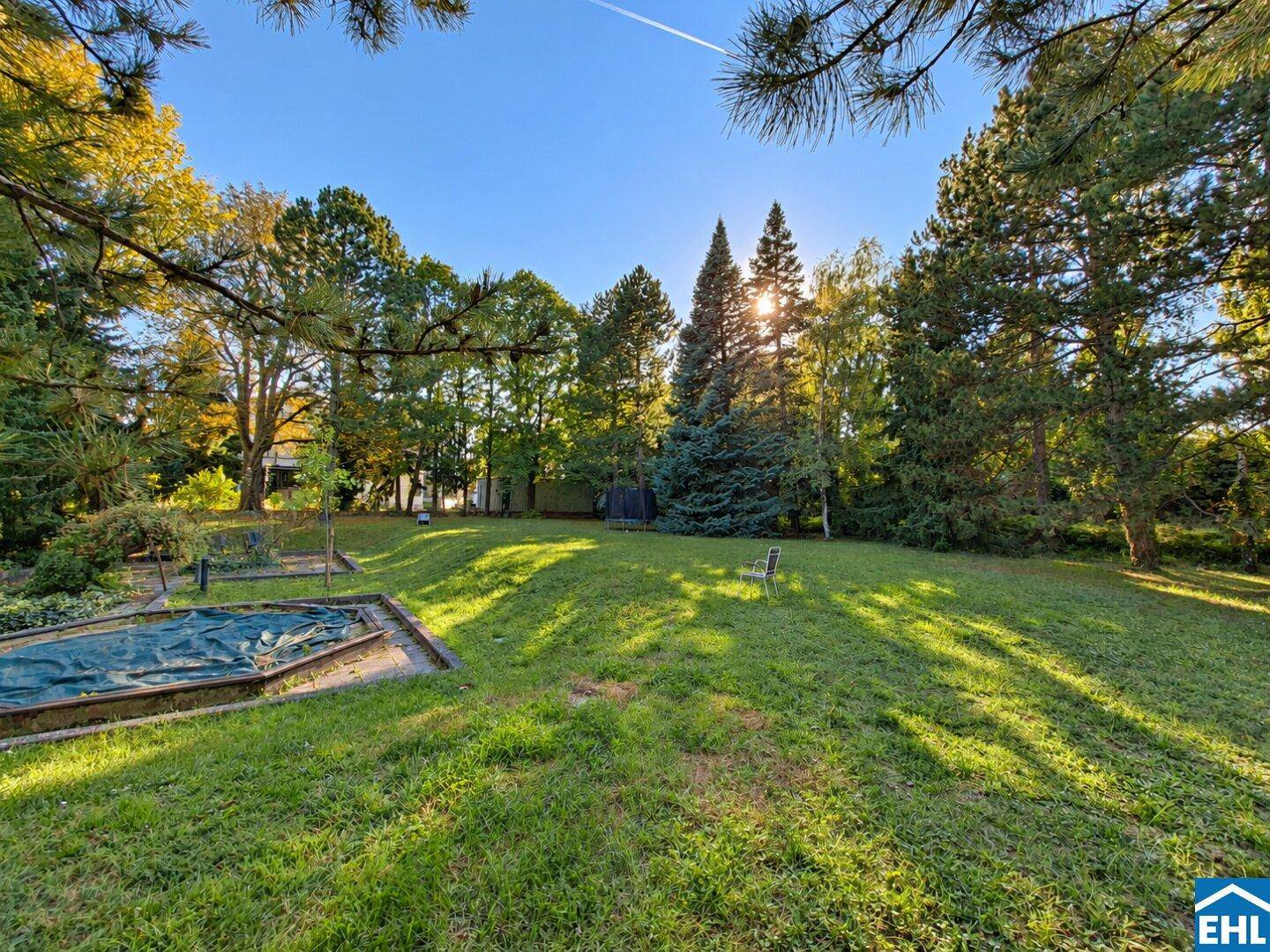 Weitläufiger Garten mit großer Rasenfläche und altem Baumbestand, bietet viel Platz im Freien.