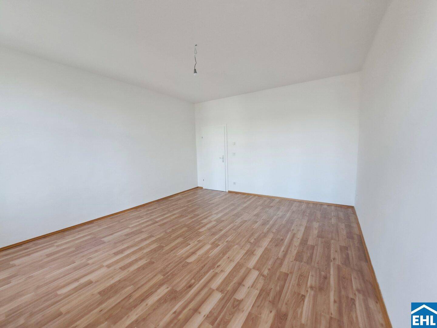 Geräumiges, helles Zimmer mit Laminatboden und weiß gestrichenen Wänden, ideal für vielfältige Nutzung.