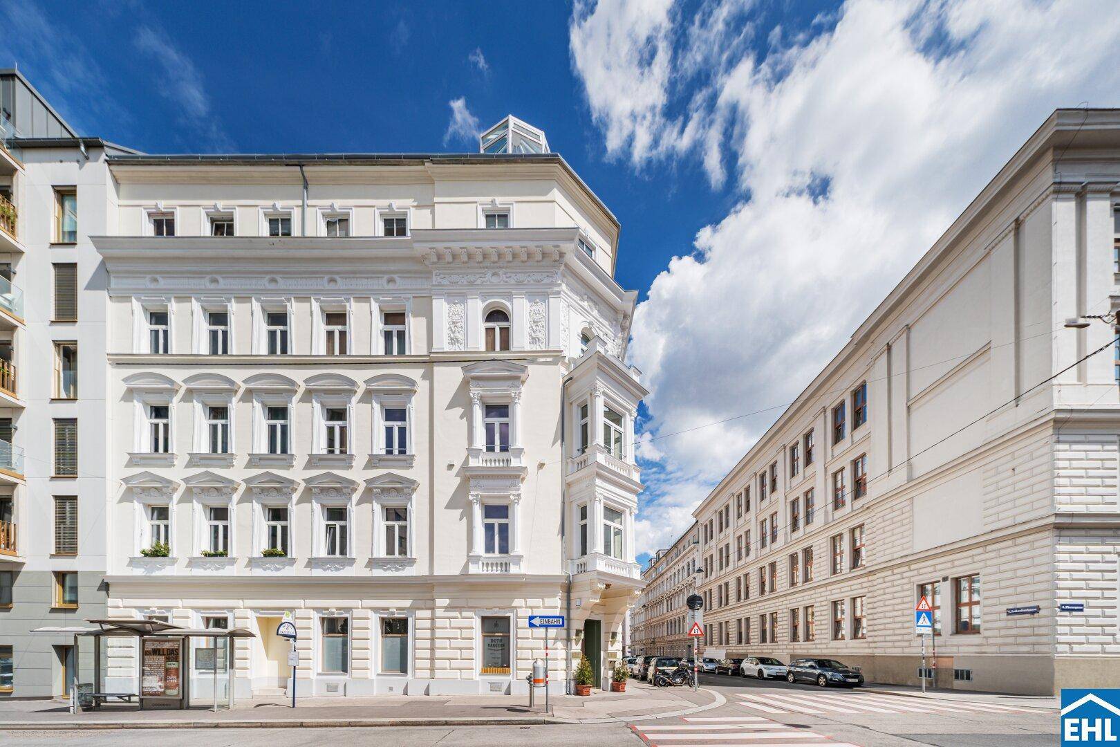 Historisches Gebäude mit eleganter Fassade und Erkerfenstern an einer städtischen Kreuzung.