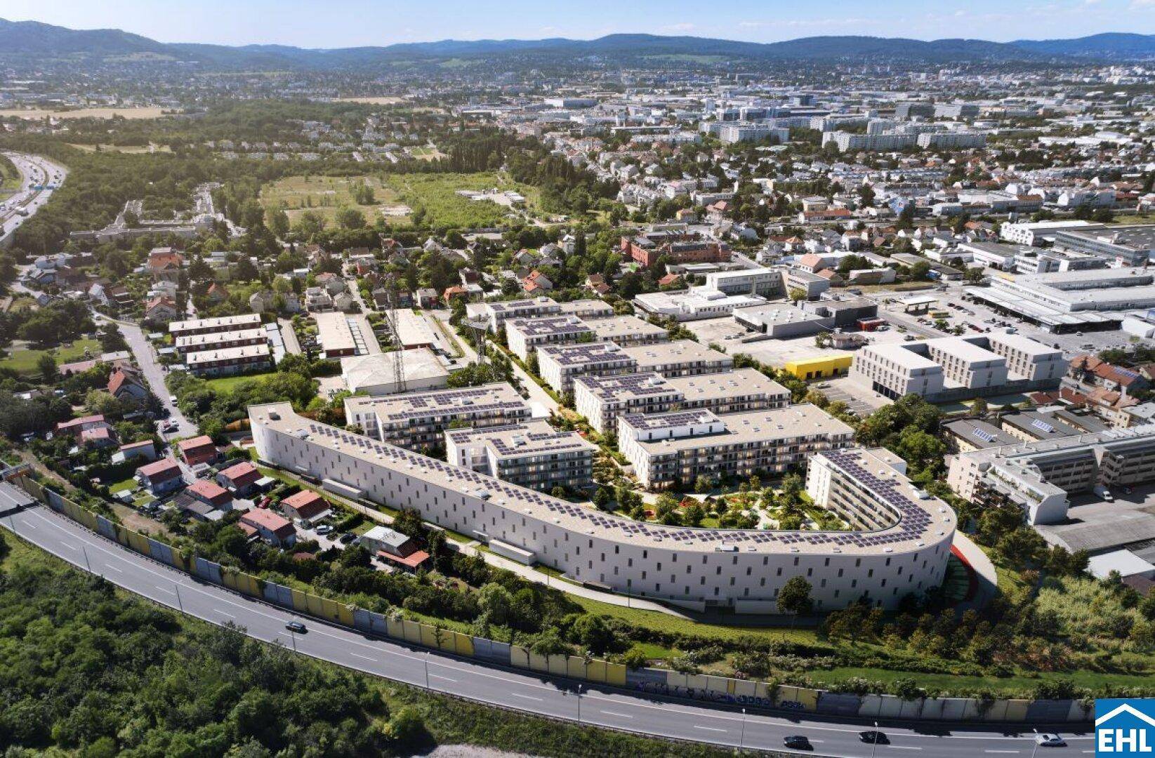 Luftaufnahme eines modernen Wohnkomplexes mit geschwungener Architektur und Photovoltaikanlagen auf den Dächern.