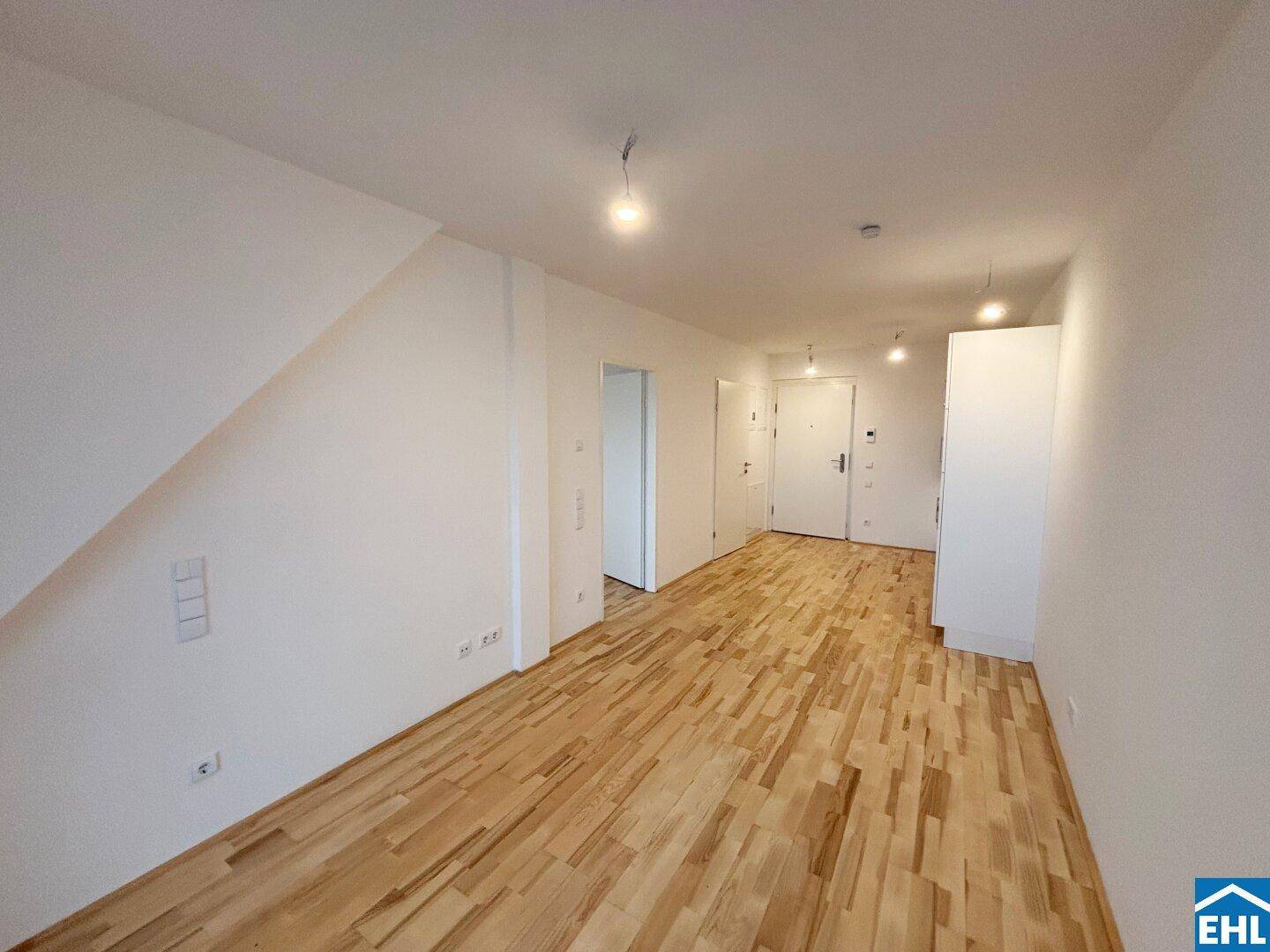 Geräumiger Flur mit Holzboden und weiß gestrichenen Wänden, der zu den verschiedenen Zimmern führt.