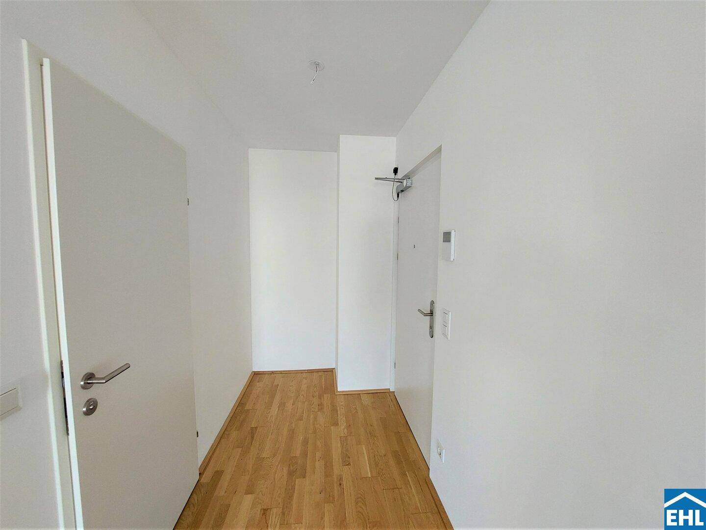 Heller Eingangsbereich mit Parkettboden und Garderobe, der zu den Wohnräumen führt.