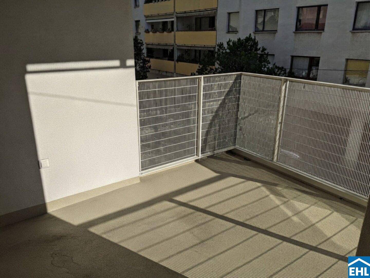 Sonniger Balkon mit Metallgeländer und Blick auf die umliegenden Gebäude.