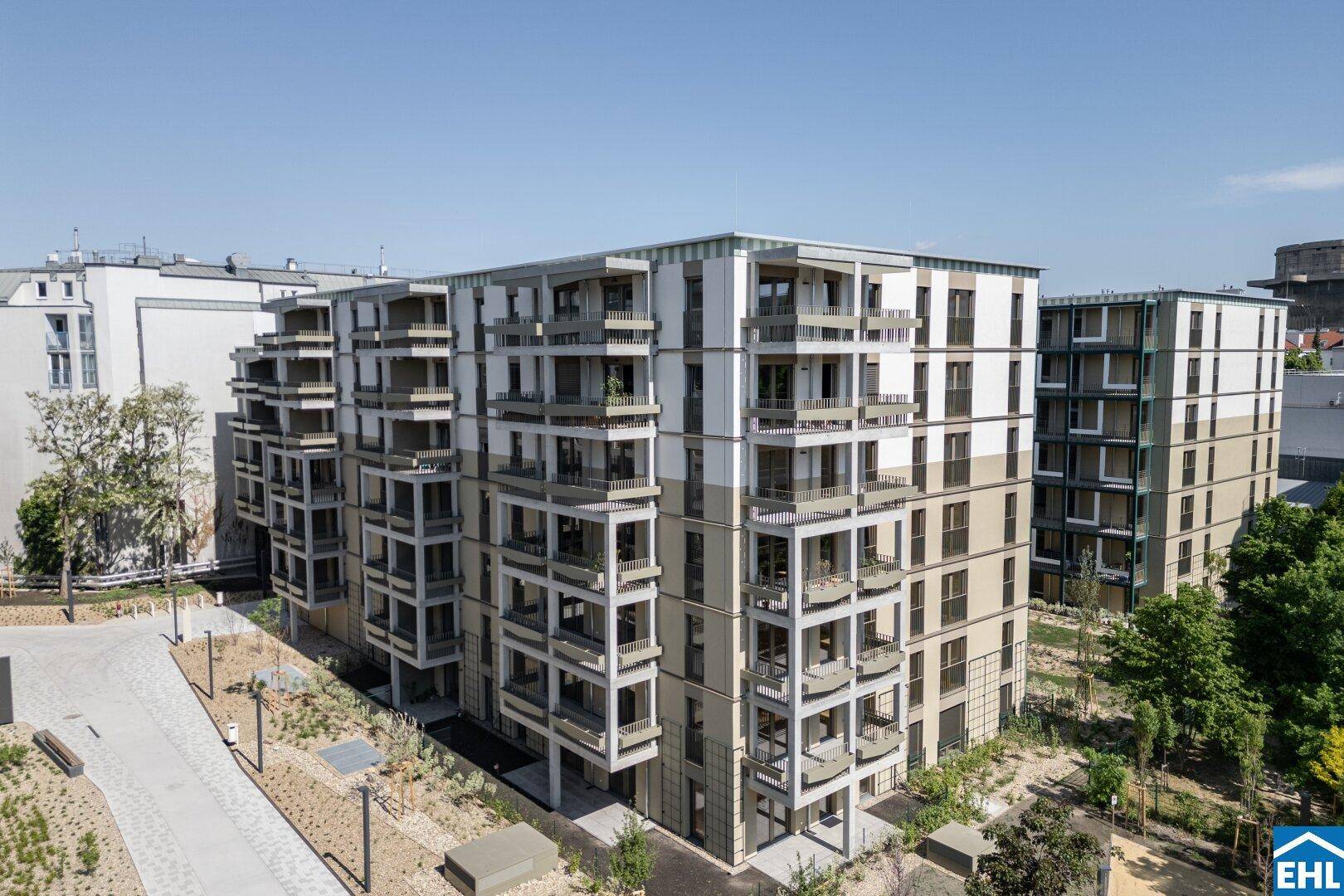 Luftaufnahme eines modernen Wohnkomplexes mit mehreren Gebäuden und begrünten Außenbereichen.