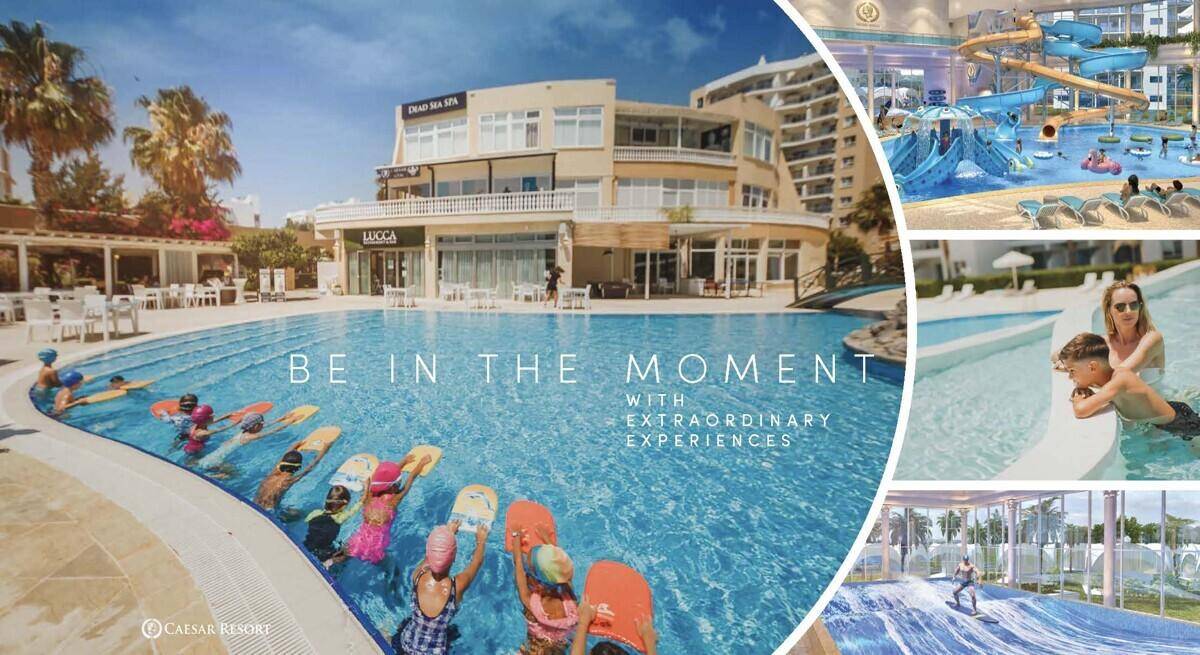 Große Poolanlage mit Kindern beim Surfkurs, umgeben von Resortgebäuden und weiteren Wasserattraktionen.