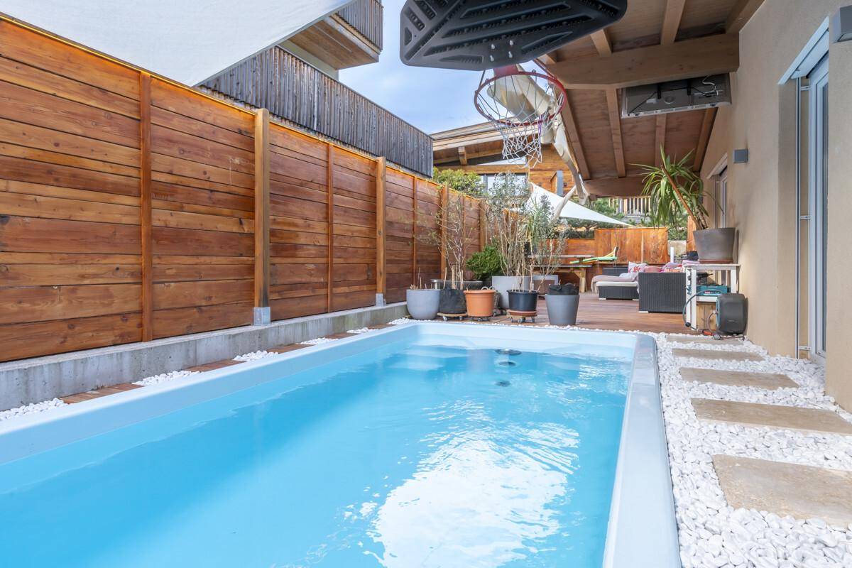 Privater Außenbereich mit kleinem Pool, Holzterrasse und Basketballkorb für Freizeitaktivitäten.