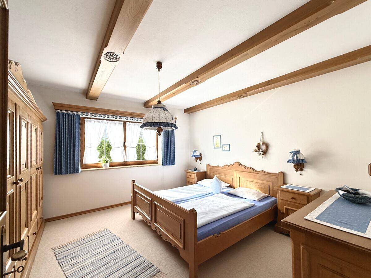 Helles Schlafzimmer mit Holzbalken, traditionellen Möbeln und Teppichboden.