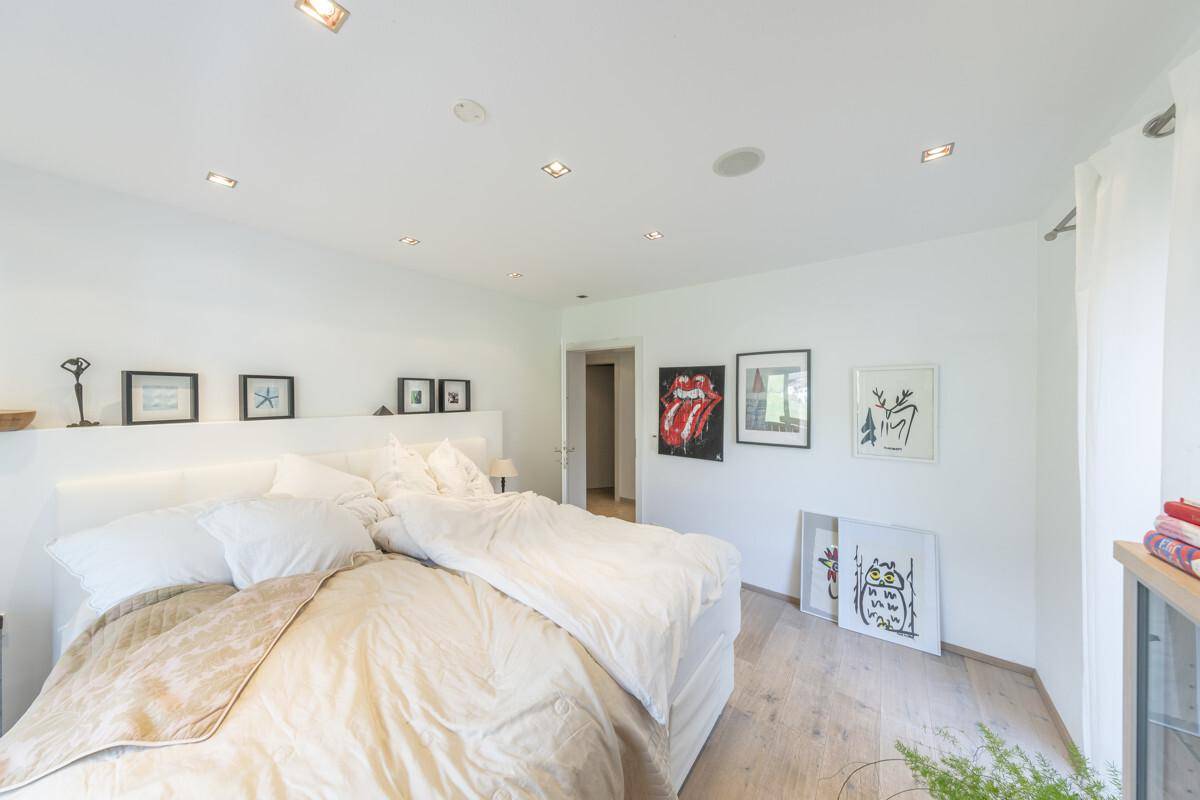 Helles Schlafzimmer mit Doppelbett, Holzboden und moderner Kunst an den Wänden.