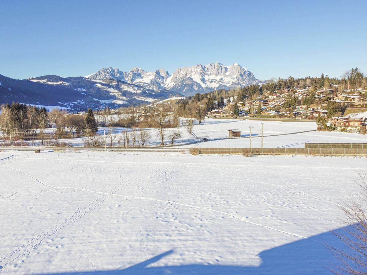 Weitläufige Winterlandschaft mit schneebedeckten Feldern und einer imposanten Bergkulisse.