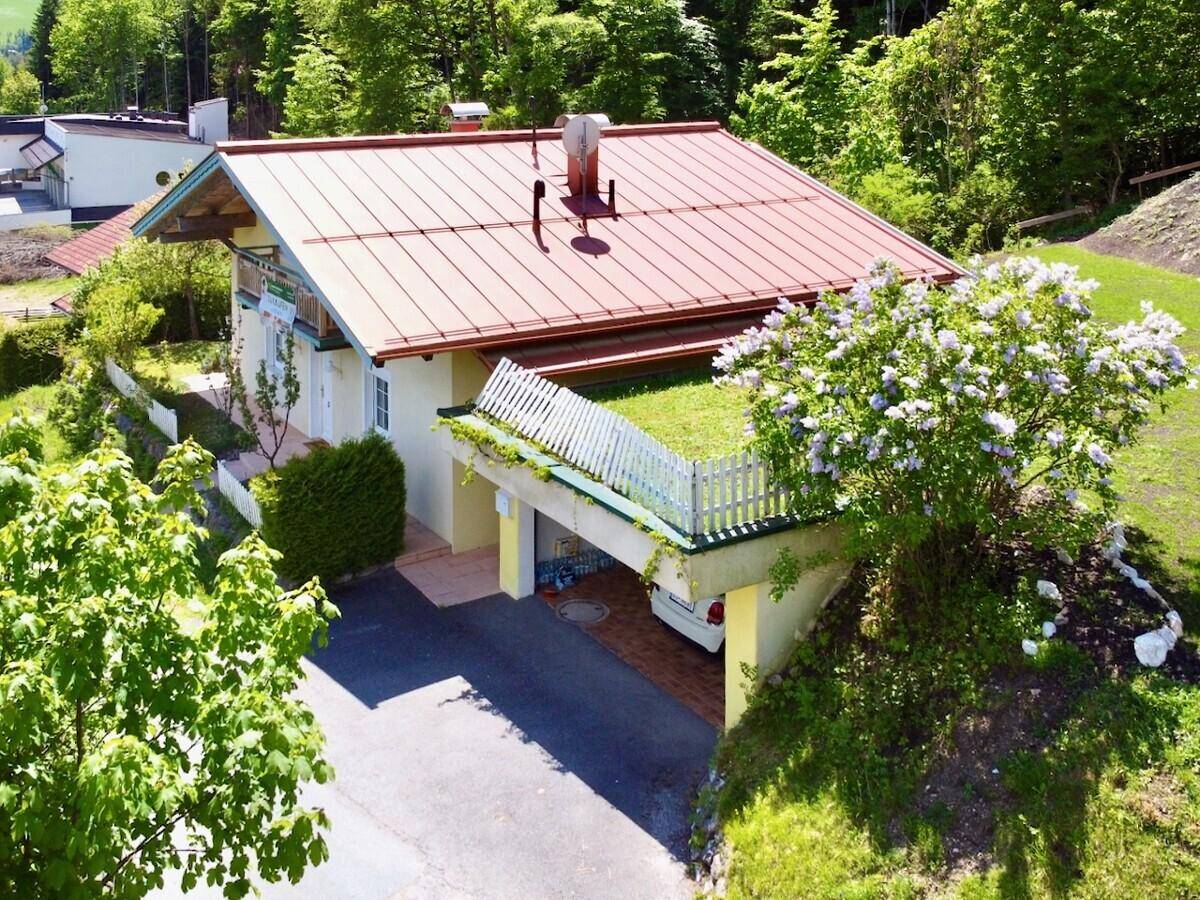 Haus mit Carport und begrüntem Dach in ländlicher Umgebung.