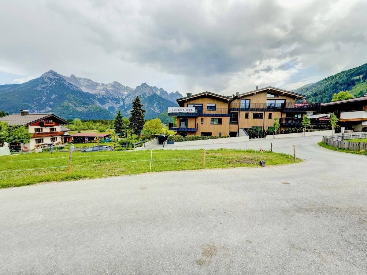 Panoramablick auf das moderne Wohngebäude mit alpiner Architektur und umliegender Berglandschaft.