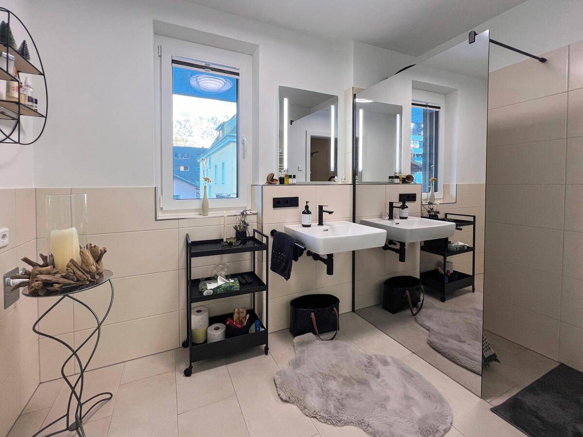 Helles Badezimmer mit Doppelwaschbecken, großem Spiegel und Fenster.