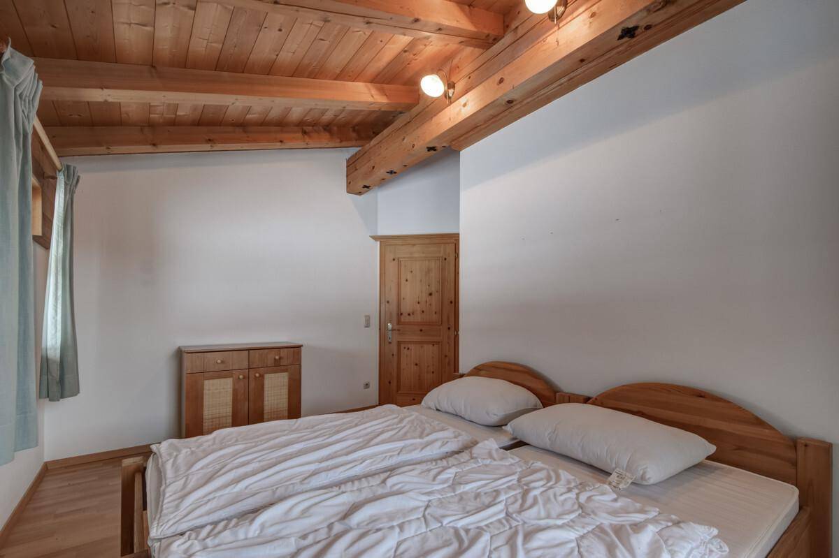 Gemütliches Schlafzimmer mit Holzbalkendecke, Parkettboden und traditioneller Holztür.