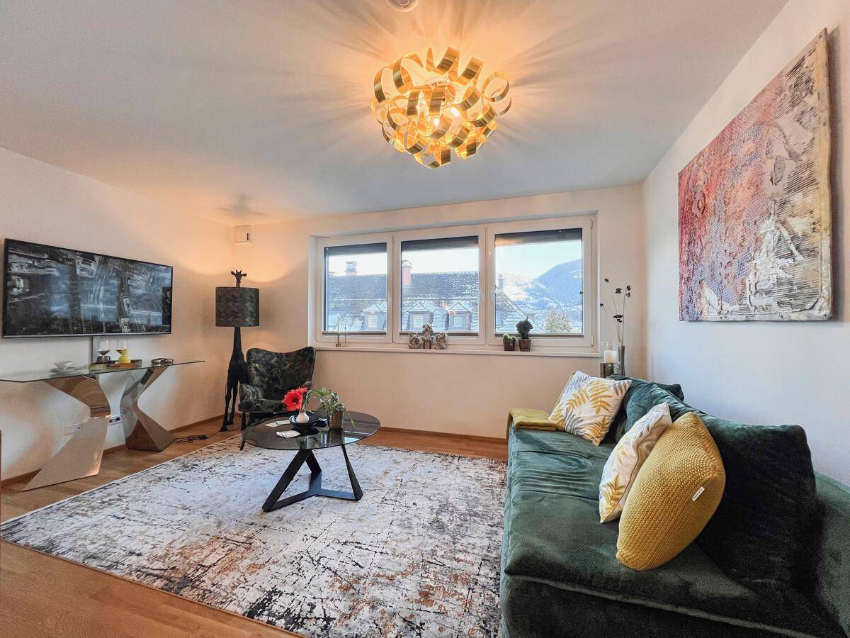Wohnzimmer mit großem Fernseher, bequemer Couch und Blick aus dem Fenster.