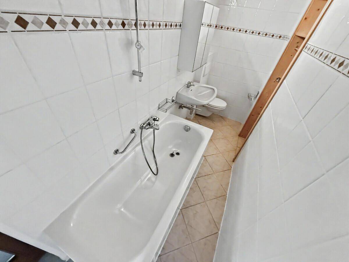 Klassisches Badezimmer mit Badewanne, Waschbecken und Fliesen in traditionellem Muster.