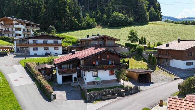 Traditionelles Wohnhaus mit rotem Ziegeldach und gepflegtem Garten in ländlicher Umgebung.