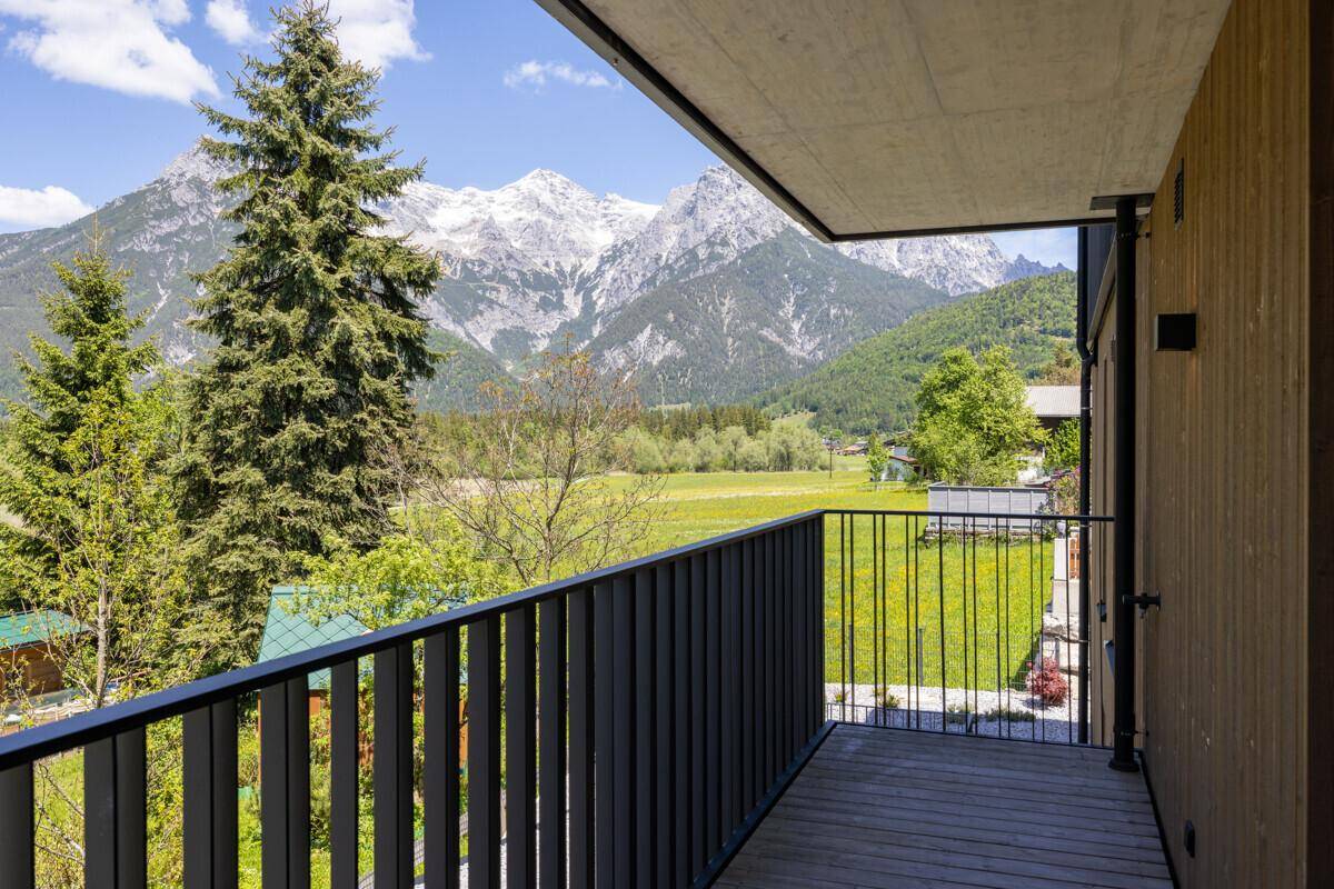Geräumiger Balkon mit atemberaubendem Blick auf die schneebedeckten Berge und grüne Wiesen.