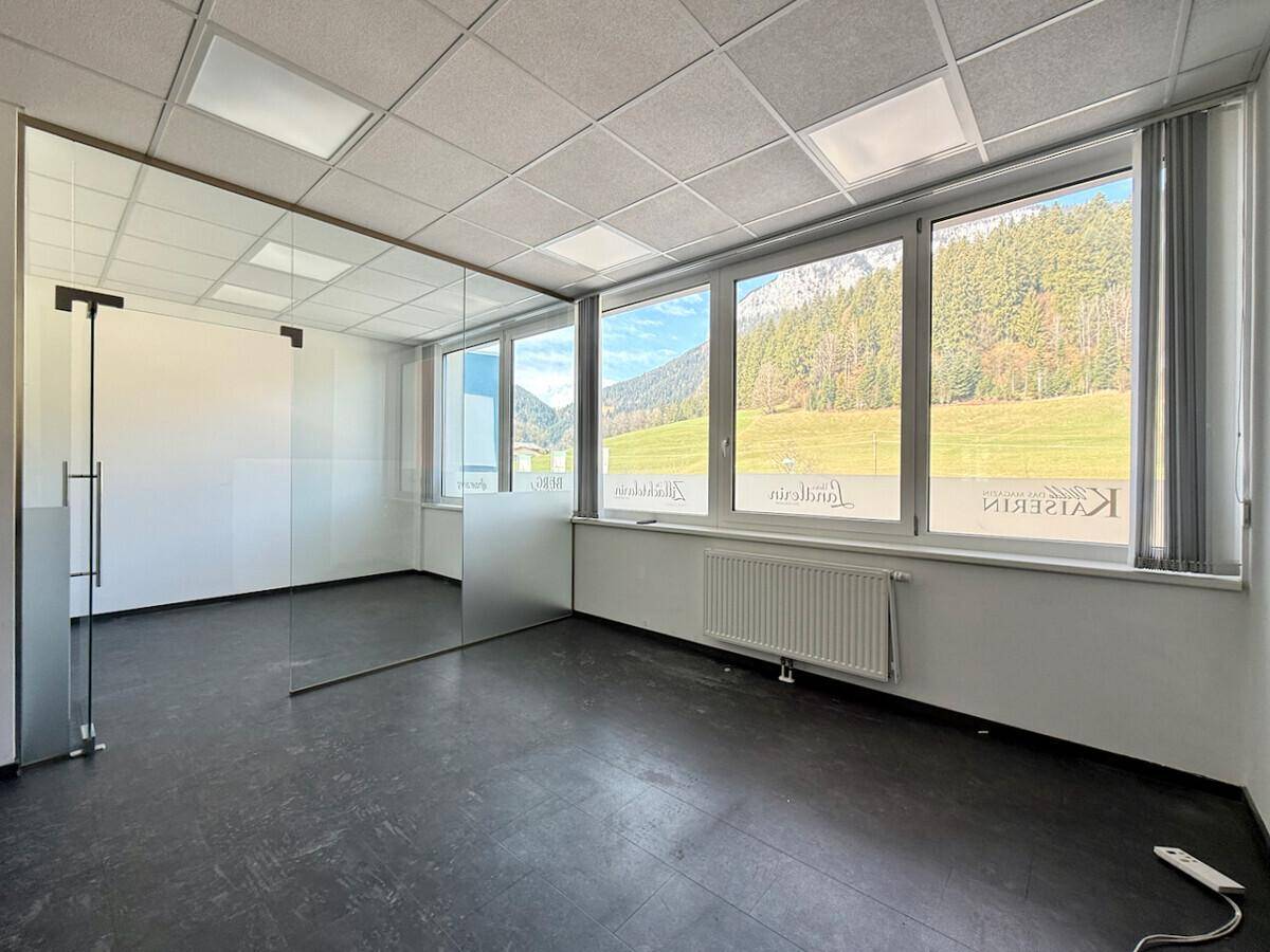 Helles Büro mit großen Fenstern, die einen weiten Blick auf die Berge und grüne Landschaft bieten.
