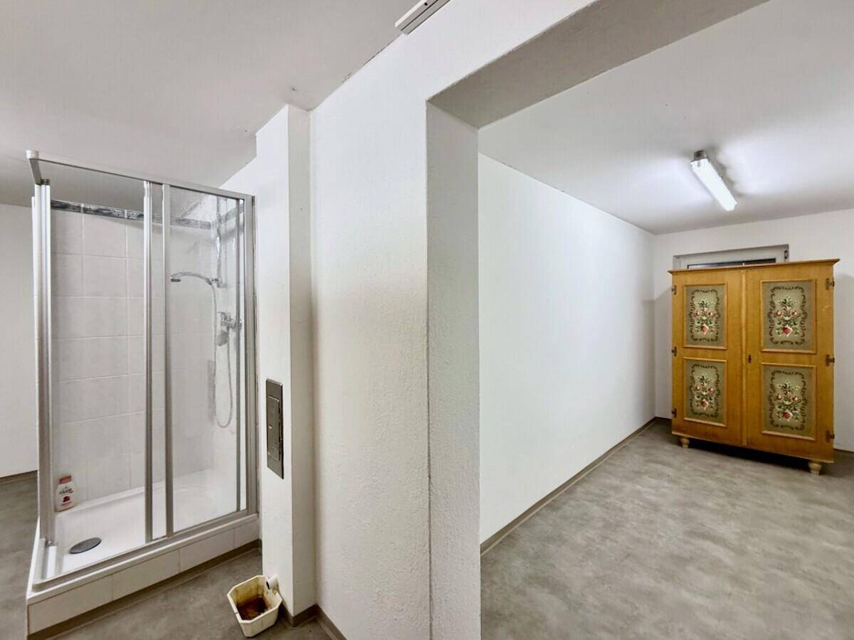 Untergeschossbereich mit Duschkabine und einem traditionellen bemalten Holzschrank.