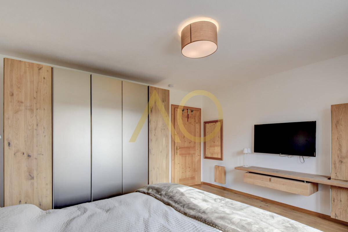 Schlafzimmer mit modernen Einbauschränken, Holzelementen und einem an der Wand montierten Fernseher.