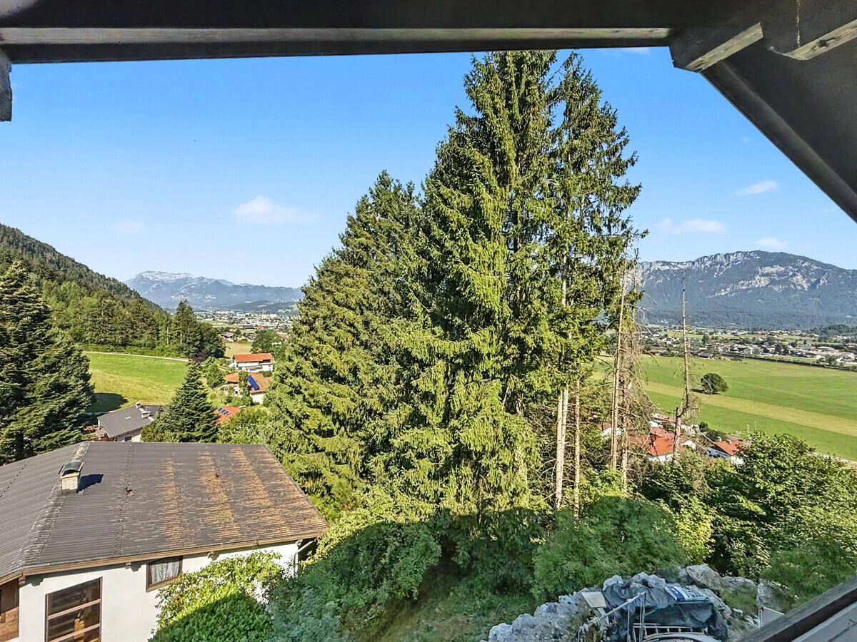 Malerischer Ausblick vom Balkon auf grüne Hügel, Wälder und ferne Berge.