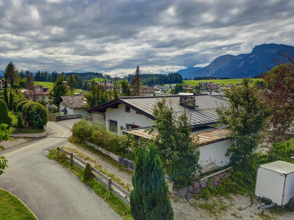 Luftaufnahme des Hauses in einer Wohngegend mit Straßen und Bergen im Hintergrund.